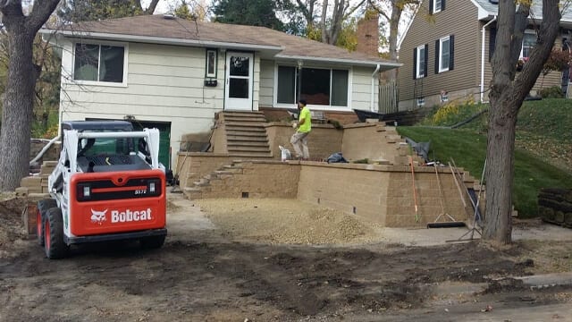 Paver stones used to create a retaining wall and stairs for front yard landscaping. 