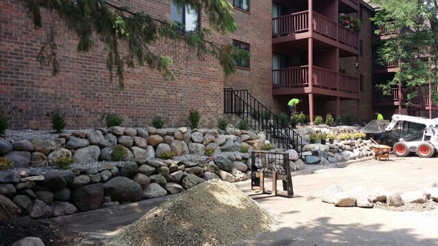 Boulder wall install with decorative shrubs done by All Metro Services.