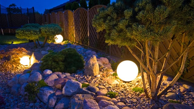 A home garden at night, illuminated by globe shaped lights for backyard landscaping.